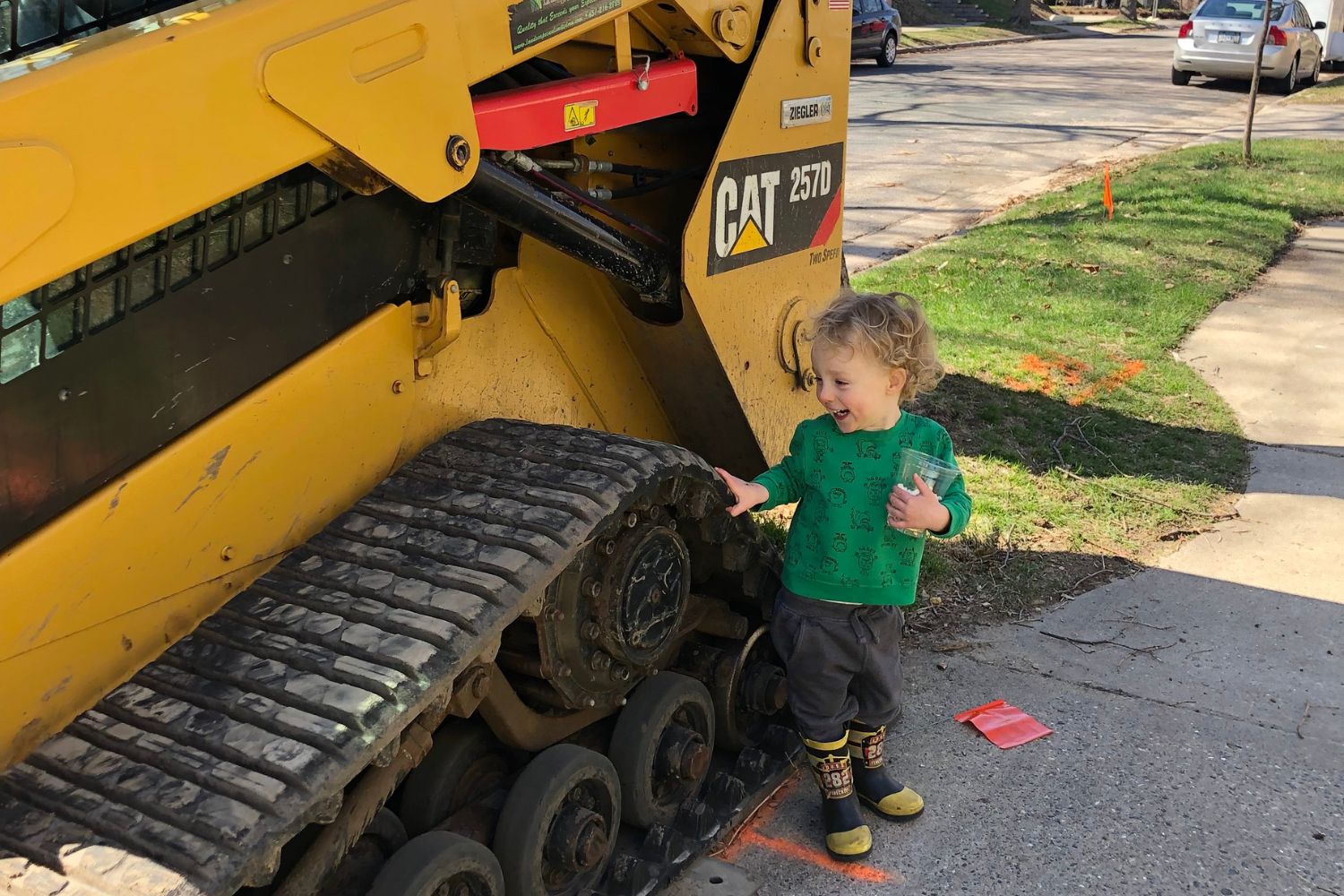 toddler excitedly looking at a bulldozer on a spring day