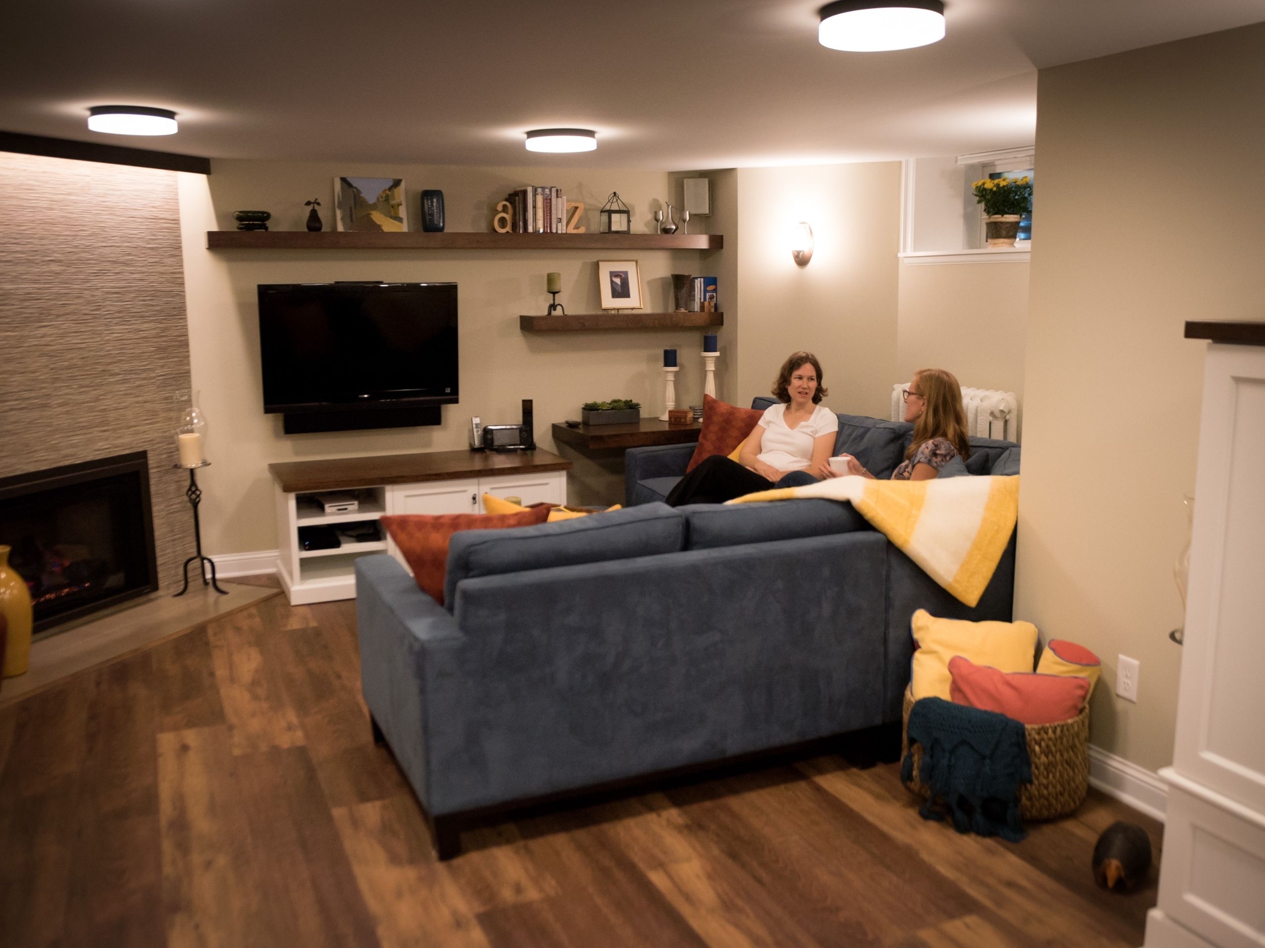 basement remodeling ideas: Basement fireplace and tv area with two people talking on the couch