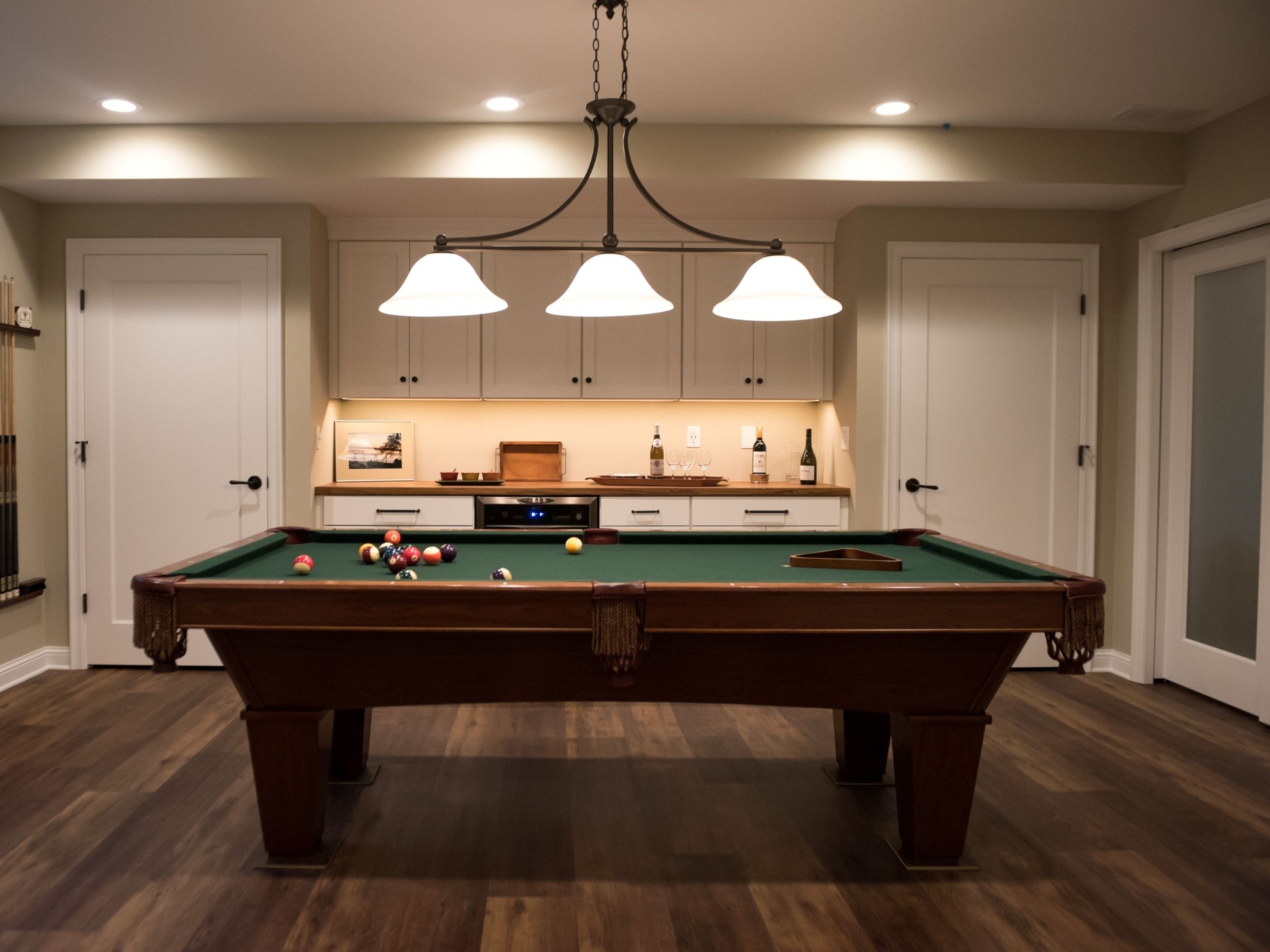 basement remodeling ideas: Basement pool table with wine bar in background and overhead light fixtures 