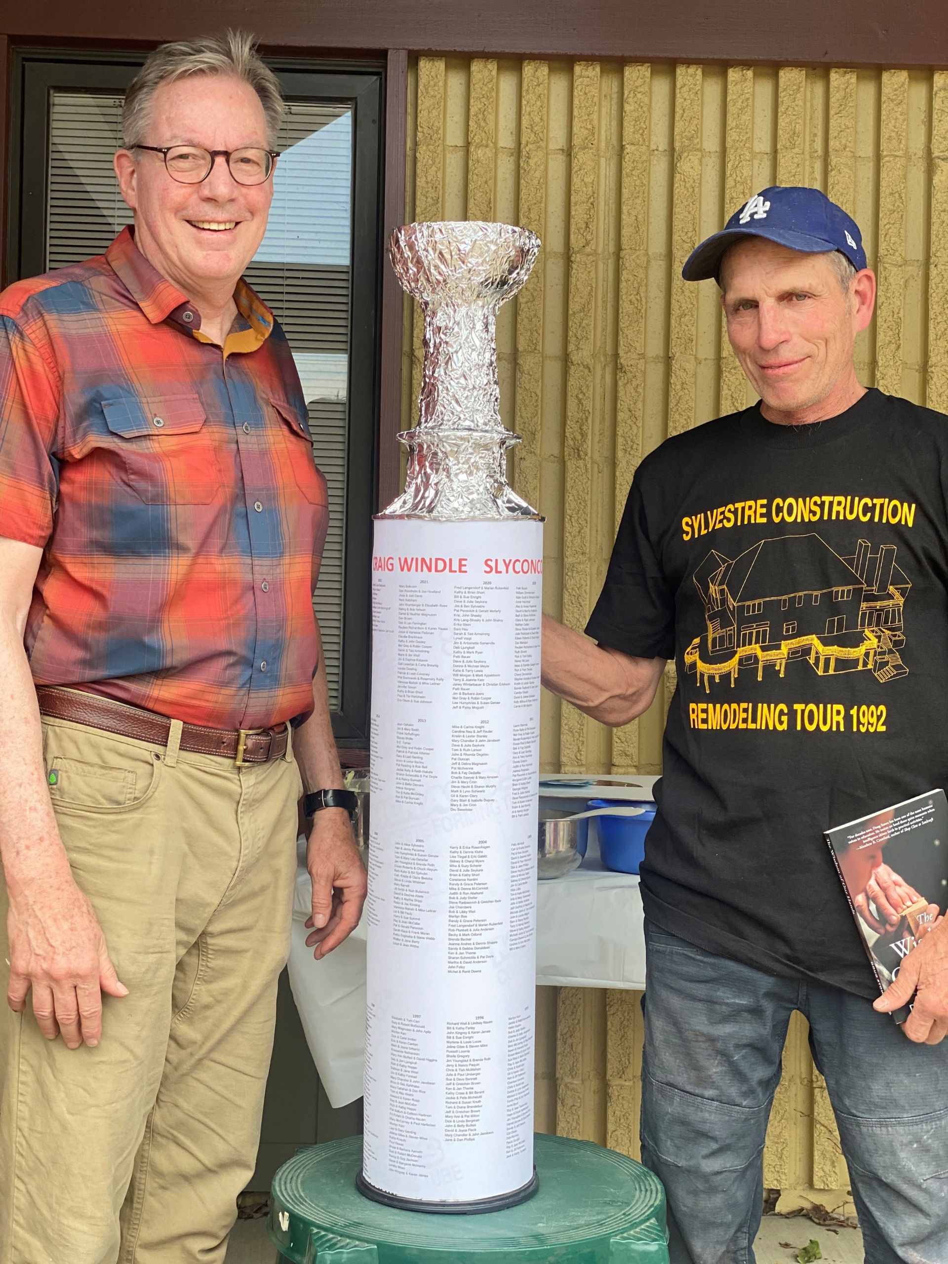 what's the story - owner John Sylvestre and newly retired carpenter Craig Windle in front of his 30 years of jobs cup trophy