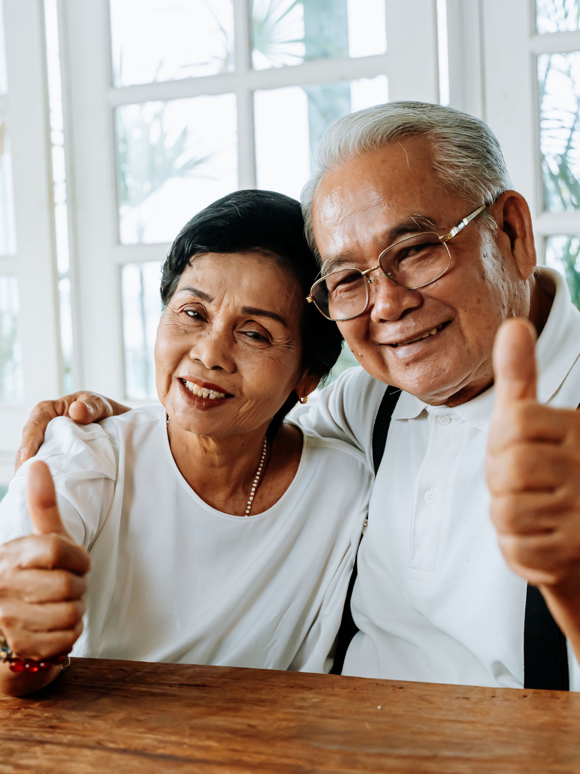 Elderly couple at table happy and smiling with thumbs up