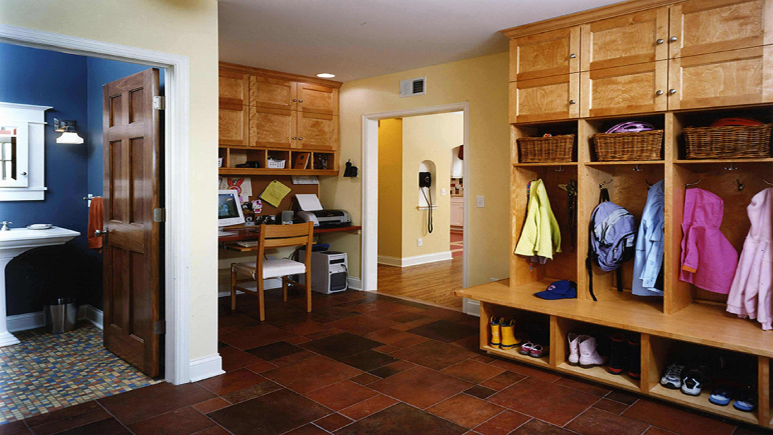 Entryway of a home with wooden cabinet storage cubbies filled with jackets and backpacks