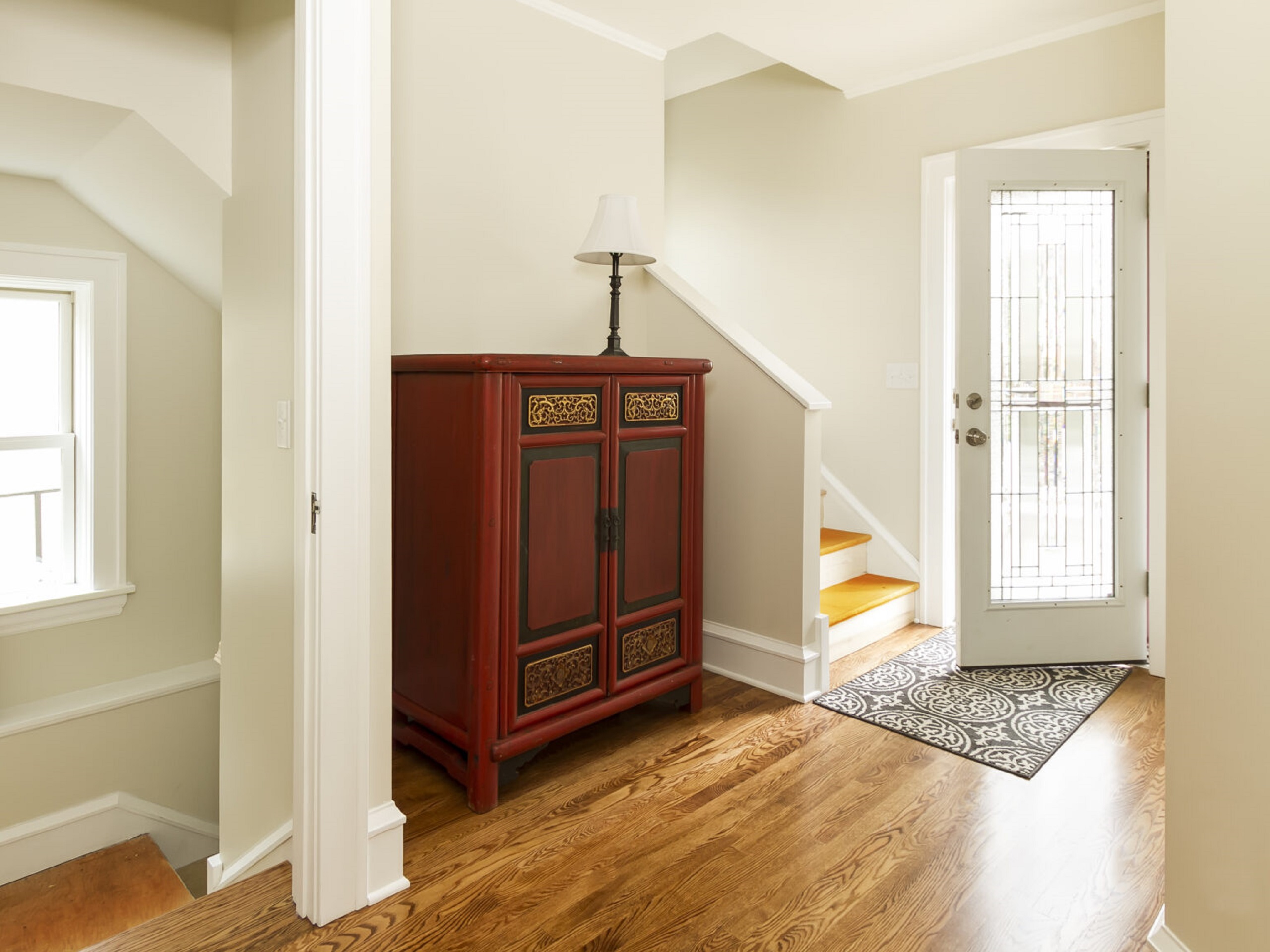 A functional entryway with an open door, rug, wooden flooring, and entryway organization space. 