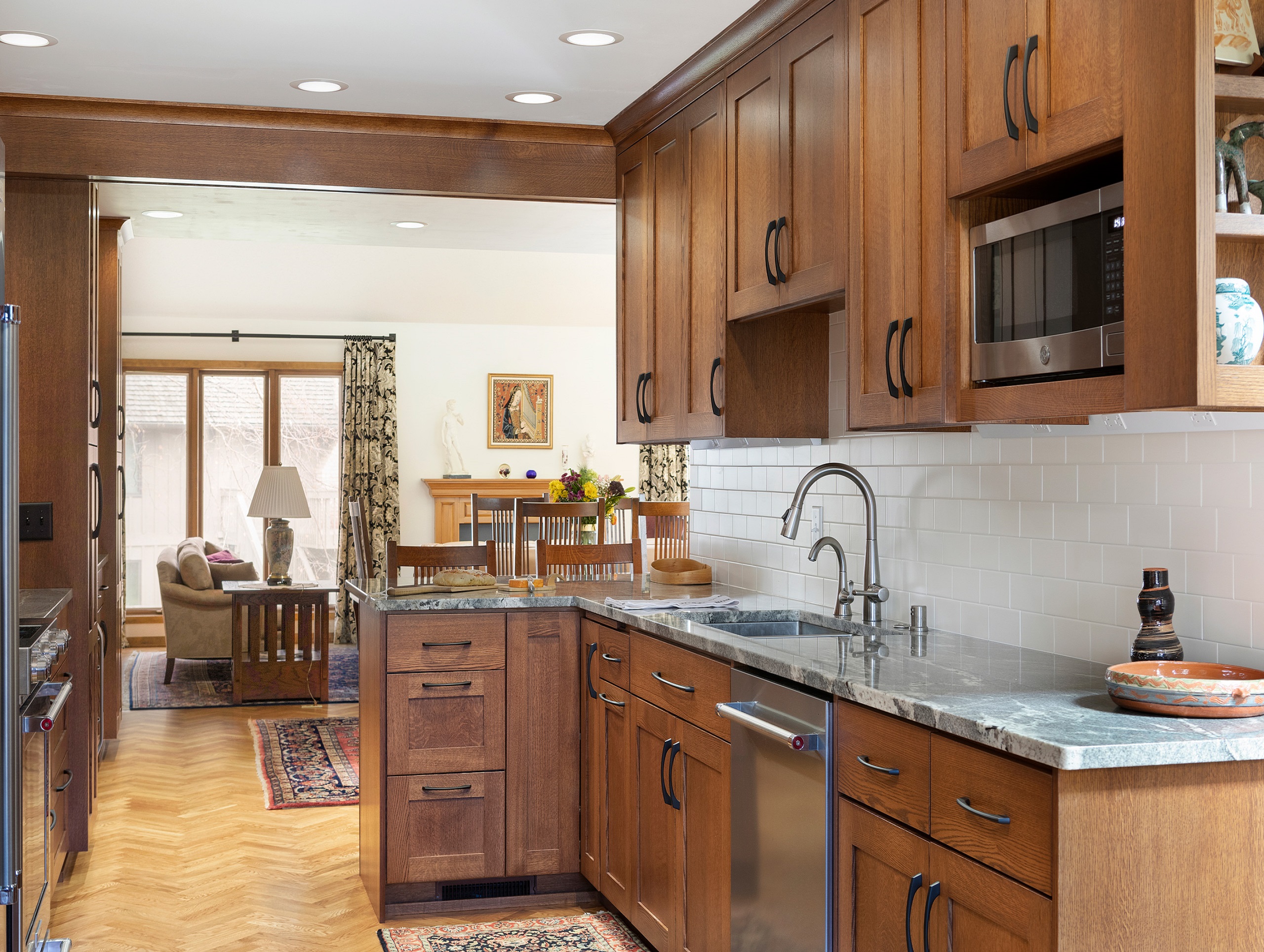 Timeless kitchen with brown cabinetry, marble counters, and hardwood floors.