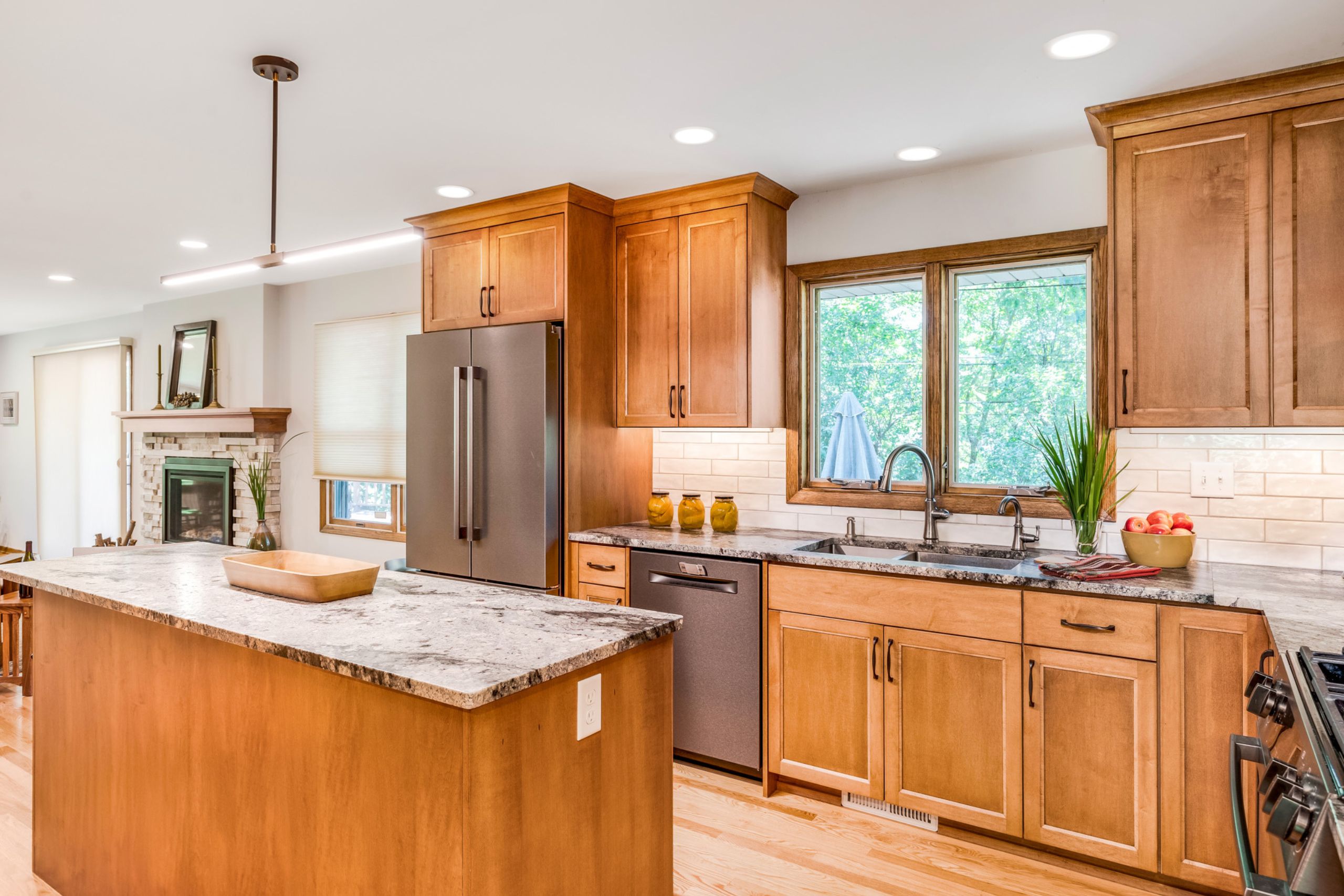 Brightly lit kitchen showing stainless appliances, center island, new cabinets, window over sink